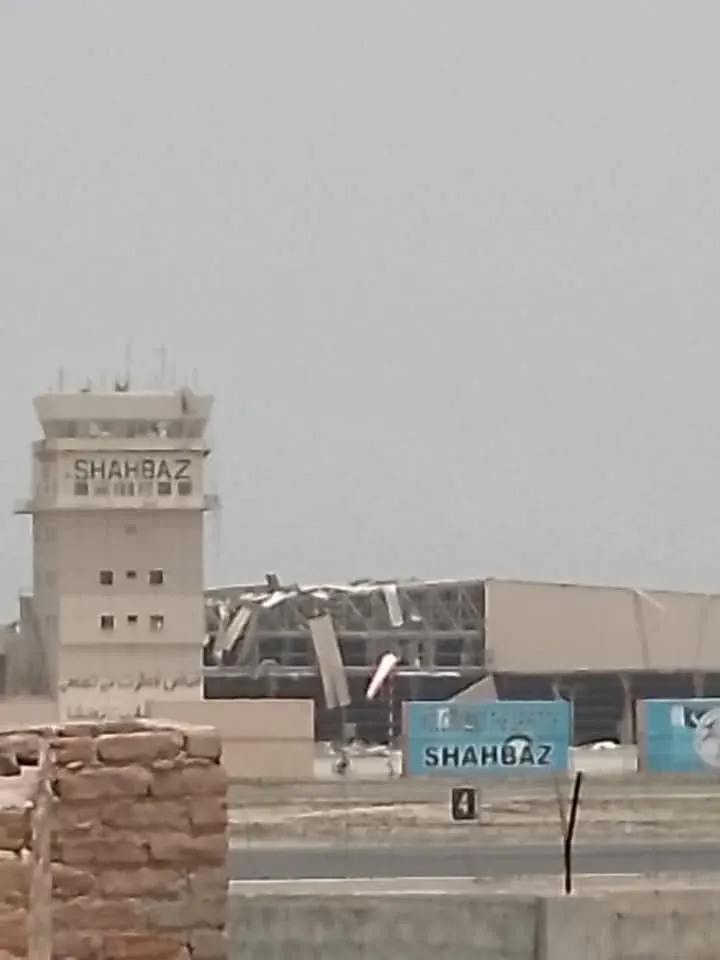 Ground-level view of PAF Base Shahbaz at Jacobabad, the control tower lettered SHAHBAZ with the main hangar's collapsed roof structure behind it